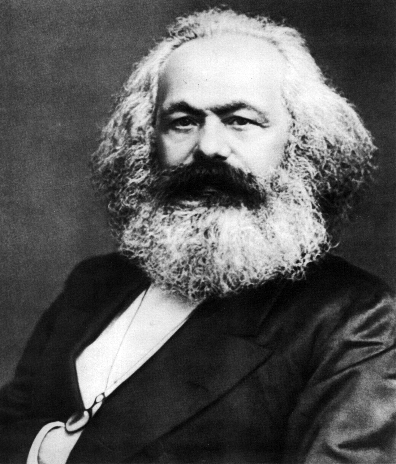 Photographie en noir et blanc de Karl Marx, prise par John Mayall en 1875. Homme âgé à l'épaisse barbe et chevelure blanches, vêtu d'un costume sombre, regard intense.